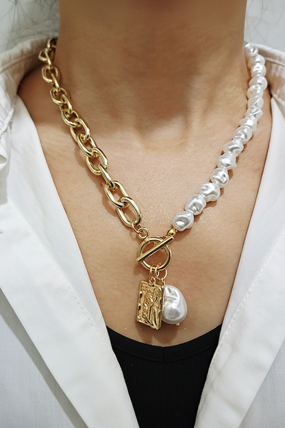Baroque pearl and gold chain necklace with coin pendant worn over a white linen top